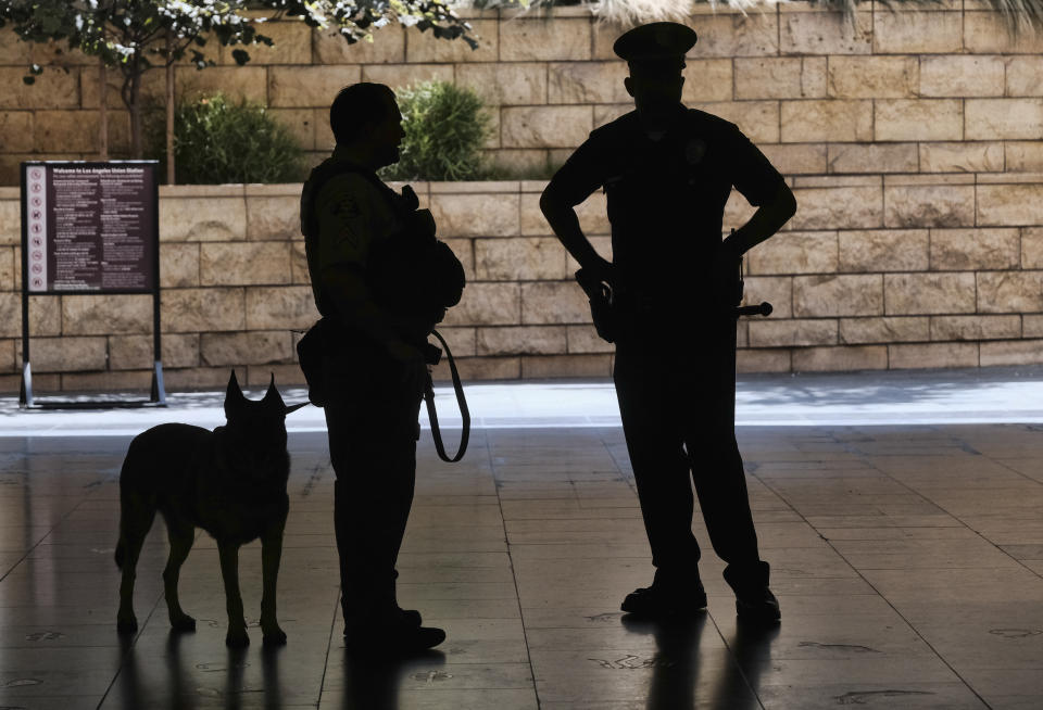 Los Angeles Metro Police and K-9 stand at the entrance to Union Station in Los Angeles on Tuesday, Aug. 14, 2018 prior to a news conference by The Transportation Security Administration (TSA) administrator David P. Pekoske. Pekoske talked about the ThruVision suicide vest-detection technology that reveals a suspicious objects on people. Aiming to stay ahead of an evolving threat against transit systems worldwide, officials in Los Angeles are testing out the airport-style body scanners that screen subway passengers for weapons and explosives. (AP Photo/Richard Vogel)