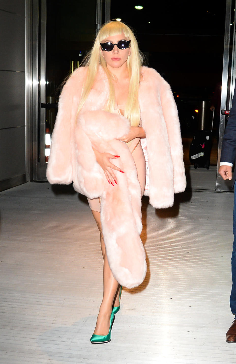 Lady Gaga wears a pink mini dress and matching faux-fur stole at JFK airport.