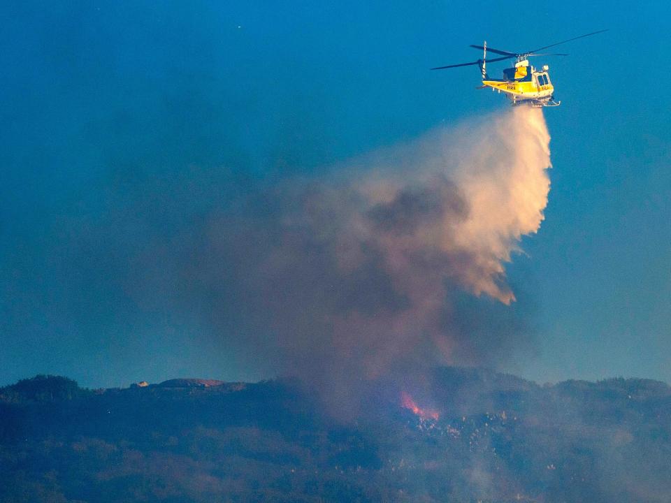 A helicopter makes a water dump.