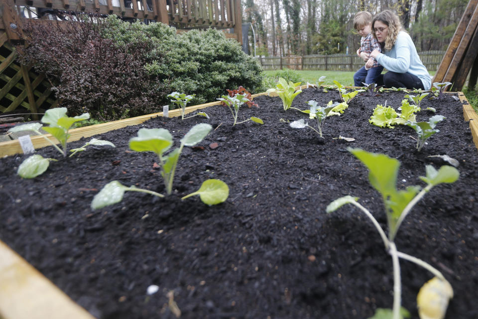 Stephanie Owens looks over the garden with her son, Cole, as they tend to it at their home Wednesday March 25 , 2020, in Glen Allen, Va. Owens is a pharmacist who has had to continue to go to work, but has been able to spend more time with her kids because they are home from school . One of the activities that they have done is planting the garden. (AP Photo/Steve Helber)