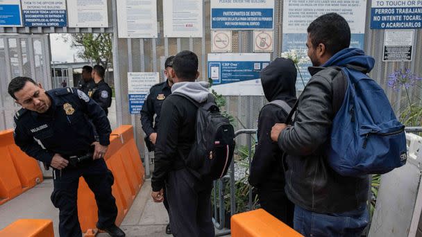 PHOTO: U.S. Customs and Border Protection agents allow asylum seekers from Venezuela to enter the country at the San Ysidro crossing port on the US-Mexico border, as seen from Tijuana, Baja California state, Mexico, May 31, 2023. (Guillermo Arias/AFP via Getty Images)