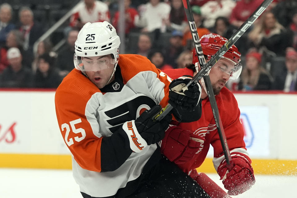 Philadelphia Flyers center Ryan Poehling (25) eyes the puck as Detroit Red Wings defenseman Justin Holl (3) defends during the third period of an NHL hockey game, Thursday, Jan. 25, 2024, in Detroit. (AP Photo/Carlos Osorio)