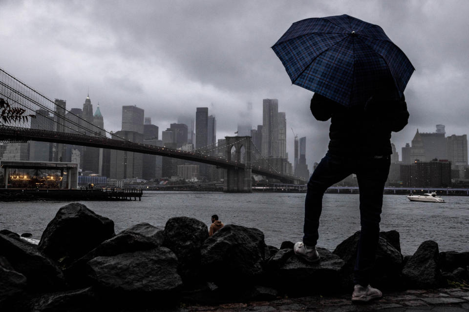 FILE - A man stands near the East River and Brooklyn Bridge with the New York skyline in the background on a Saturday, Oct. 1, 2022. Starting this week, job-seekers in New York City will have access to a key piece of information: how much money they can expect to earn for an advertised opening.(AP Photo/Julia Nikhinson)