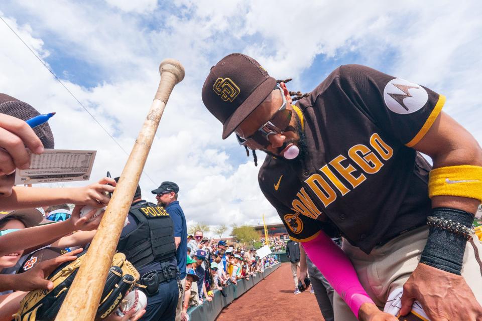 Fernando Tatis Jr. signs autographs before a spring training game.