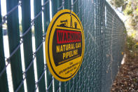 A warning sign marks a natural gas pipeline outside a compressor station on Monday, Oct. 25, 2021, in Dalworthington Gardens, Texas, a small municipality that's tucked within the city of Arlington. Compressor stations like this one change the pressure of the natural gas to help move it through the lines. Increasingly, natural gas ends up at facilities on the Gulf Coast where it is converted into liquid natural gas, or LNG, so it can be shipped to Europe, Asia and other parts of the world. Natural gas is used to heat homes and for cooking, among other things. (AP Photo/Martha Irvine)