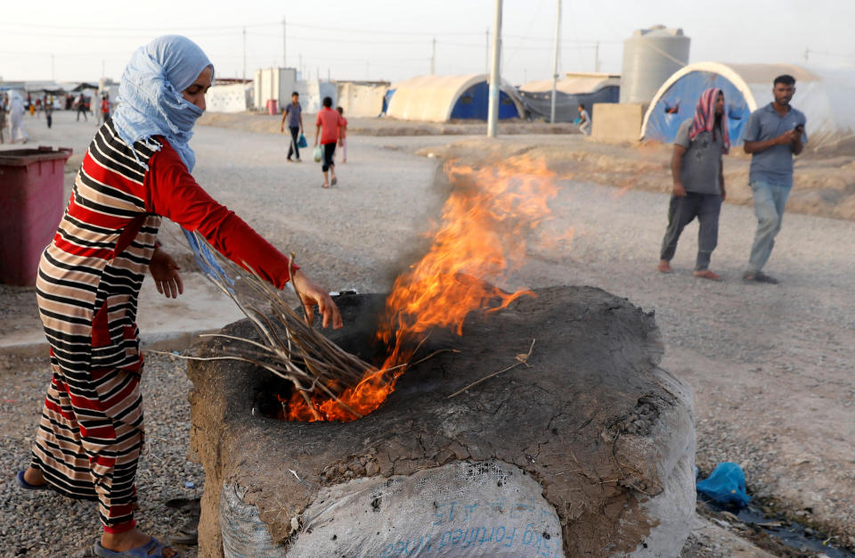 A displaced Iraqi woman from Mosul use fire to heat a makeshift oven to bake bread for Iftar, during the Muslim holy month of Ramadan at a refugee camp al-Khazir in the outskirts of Erbil, Iraq, June 10.