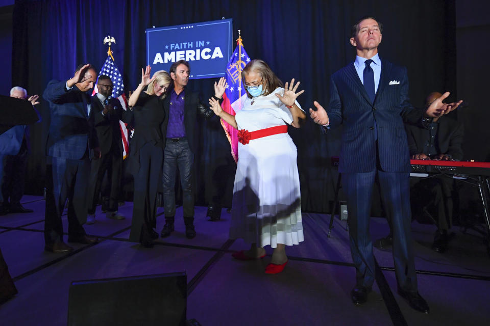 FILE - In this Thursday, July 23, 2020 file photo, from right, Ralph Reed, Dr. Alveda King, Journey keyboardist Jonathan Cain, and personal pastor to the president, Paula White Cain, and others pray on stage during a Donald Trump campaign event courting devout conservatives by combining praise, prayer and patriotism in Alpharetta, Ga. Like most fellow evangelicals, Reed left room for the president to eke out a victory even as that path appeared slim on Friday, Nov. 6, 2020. But he also singled out Democrats’ lackluster showing in key congressional races as a positive sign and suggested that religious conservatives might see an opportunity to work with a Biden administration that tacks away from the left. (AP Photo/John Amis)