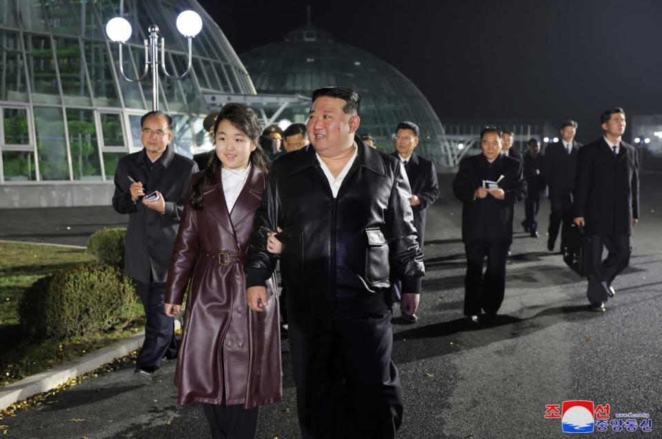 Kim Jong Un walks alongside his daughter, Kim Ju-ae, in front of a greenhouse.