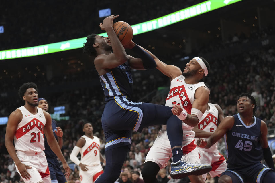 Toronto Raptors forward Bruce Brown (11) fouls Memphis Grizzlies forward Jaren Jackson Jr., center, during first half of an NBA basketball game in Toronto, Monday Jan. 22, 2024. (Nathan Denette/The Canadian Press via AP)