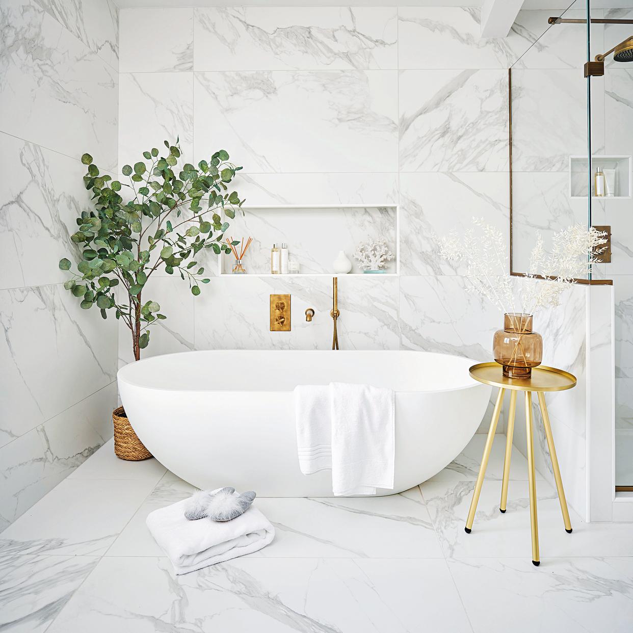  White bathroom with freestanding bath and plant. 