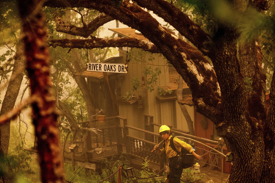 A firefighter battling the McKinney Fire protects a cabin in Klamath National Forest, Calif., on Sunday, July 31, 2022. (AP Photo/Noah Berger)