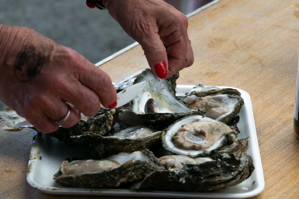 Paula Harper, from Michigan, scrapes out an oyster shell to make room for sauce at the 44th annual Fulton Oysterfest on Saturday, March 4, 2023.