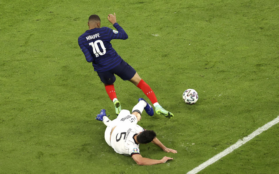 France's Kylian Mbappe, left, and Germany's Mats Hummels, right, challenge for the ball during the Euro 2020 soccer championship group F match between France and Germany at the Allianz Arena stadium in Munich, Tuesday, June 15, 2021. (AP Photo/Alexander Hassenstein, Pool)