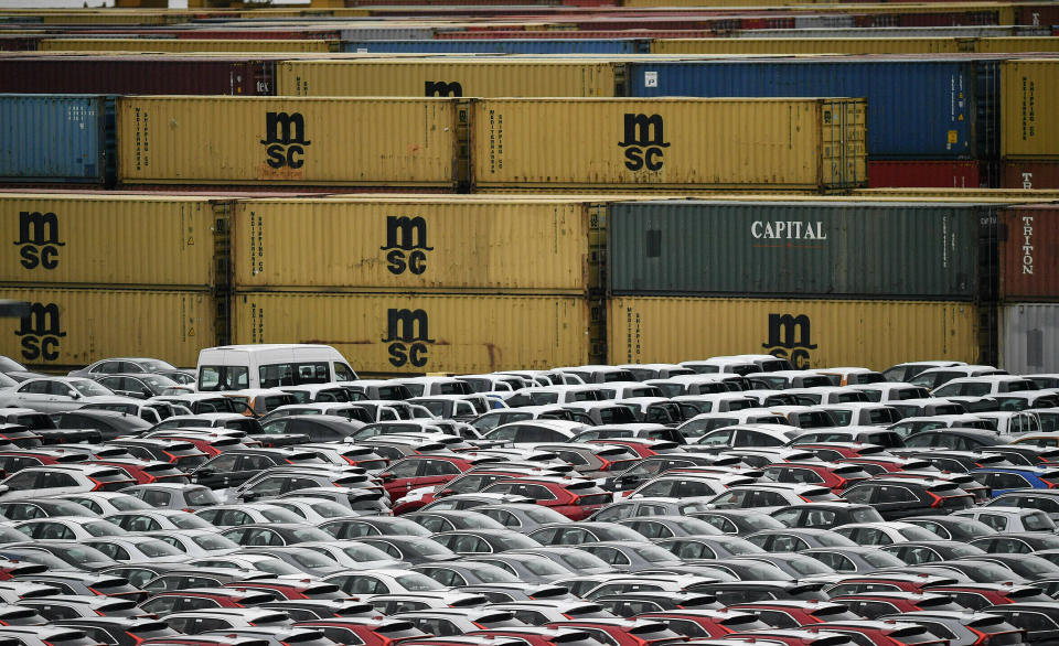 Numerosos vehículos de exportación e importación se encuentran el jueves 16 de mayo de 2019 frente a contenedores en el muelle de Bremerhaven, Alemania, que con dos millones de unidades por año es uno de los mayores centros automovilísticos del mundo. (AP Foto/Martin Meissner)