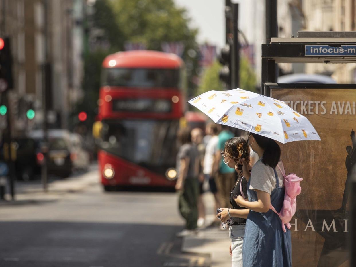 A woman, holding umbrella to protect from the Sun, walks as heatwave hits London, United Kingdom on July 18, 2022