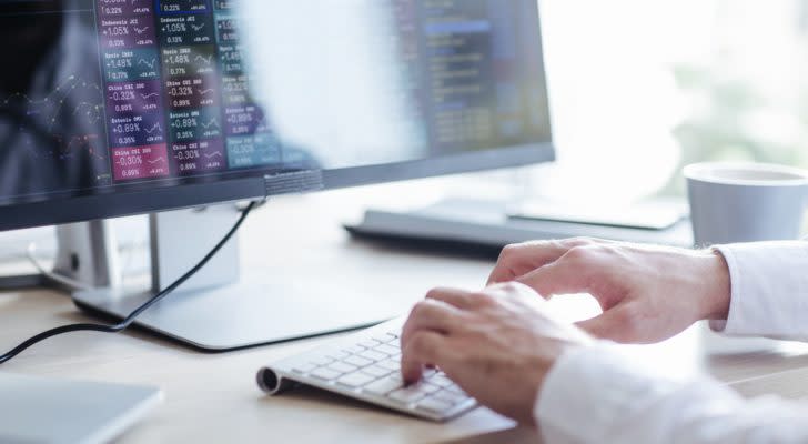 hands typing on a computer keyboard under a computer screen