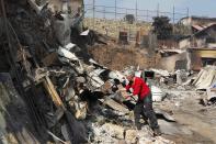 A resident works on the remains of a house after a forest fire burned several neighbourhoods in the hills in Valparaiso city, northwest of Santiago, April 13, 2014. At least 11 people were killed and 500 houses destroyed over the weekend by a fire that ripped through parts of Chilean port city Valparaiso, as authorities evacuated thousands and used aircraft to battle the blaze. REUTERS/Eliseo Fernandez (CHILE - Tags: SOCIETY ENVIRONMENT DISASTER)