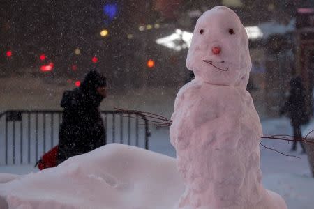 A person walks along 43rd Street past a snowman during a snow storm in Times Square in the Manhattan borough of New York, January 23, 2016. REUTERS/Carlo Allegri