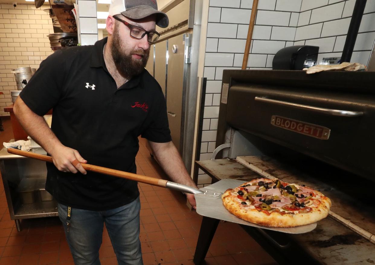 Cody Hornyak, owner of Jack's Pizza, takes a Jack's Choice pizza (pepperoni, sausage, ham, bacon, onion, mushrooms, green peppers and black olives) out of the oven at his Brimfield Township eatery.