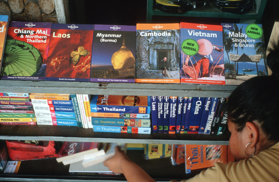 A person in a book store looking at Lonely Planet guide books