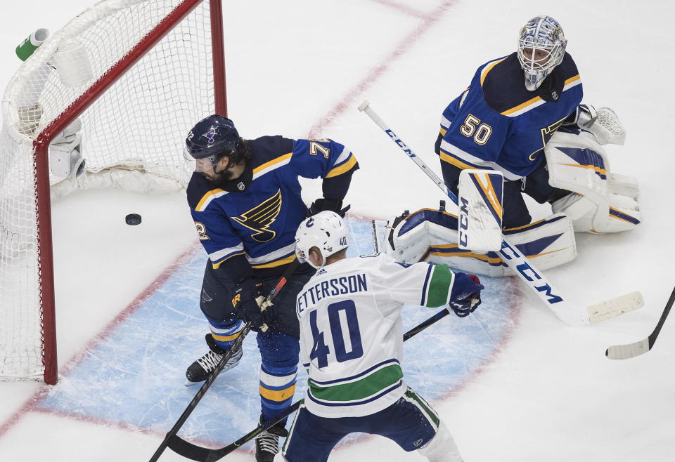 Vancouver Canucks' Elias Pettersson (40) scores a goal on St. Louis Blues goalie Jordan Binnington (50) as Blues' Justin Faulk (72) defends during the third period of an NHL hockey Stanley Cup first-round playoff series, Friday, Aug. 14, 2020, in Edmonton, Alberta. (Jason Franson/The Canadian Press via AP)