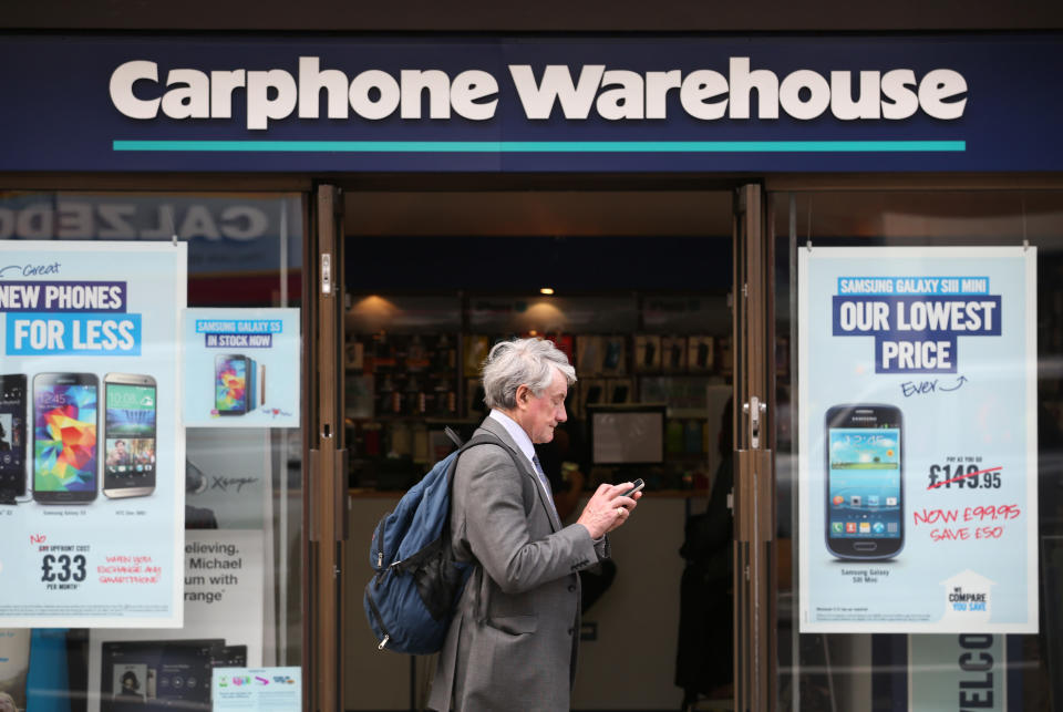 A man looks at his mobile phone as he walks past a branch of Carphone Warehouse on May 15, 2014 in London, England. Photo: Peter Macdiarmid/Getty Images