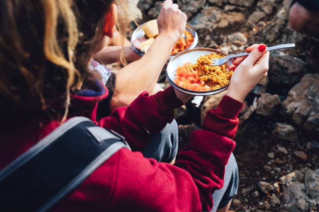 People eat food during a hike. 