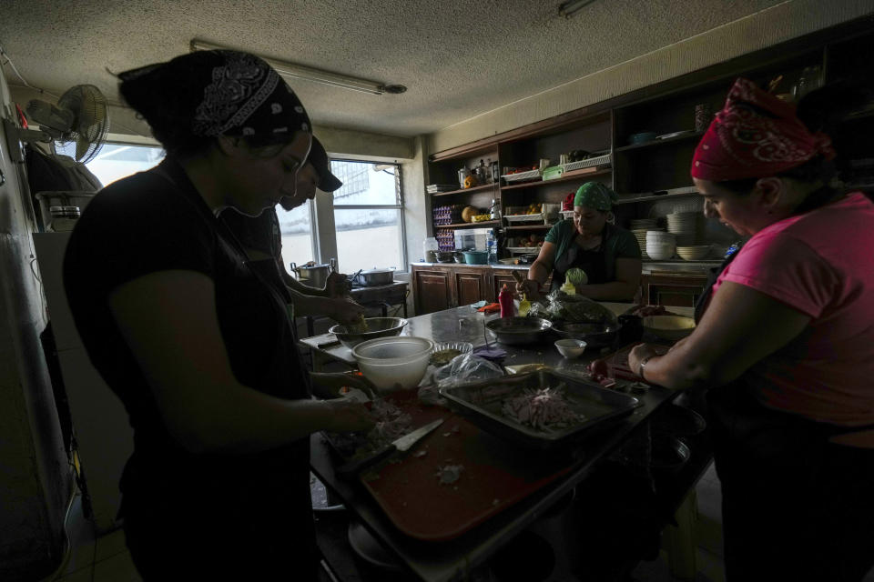 Restaurant employees carry on with their work using manual kitchen tools due to power cuts ordered by the ministry of energy, in Quito, Ecuador, Tuesday, April 16, 2024. Ecuador has started to ration electricity in its main cities as a drought linked to the El Niño weather pattern depletes reservoirs and limits output at hydroelectric plants. (AP Photo/Dolores Ochoa)