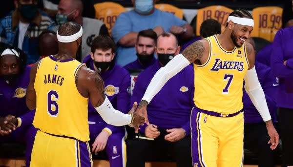 LeBron James and Carmelo Anthony of the Los Angeles Lakers touch hands in a break of action against the Golden State Warriors during their NBA season opener in Los Angeles, California on October 19, 2021. (Photo by Frederic J. BROWN / AFP) (Photo by FREDERIC J. BROWN/AFP via Getty Images)