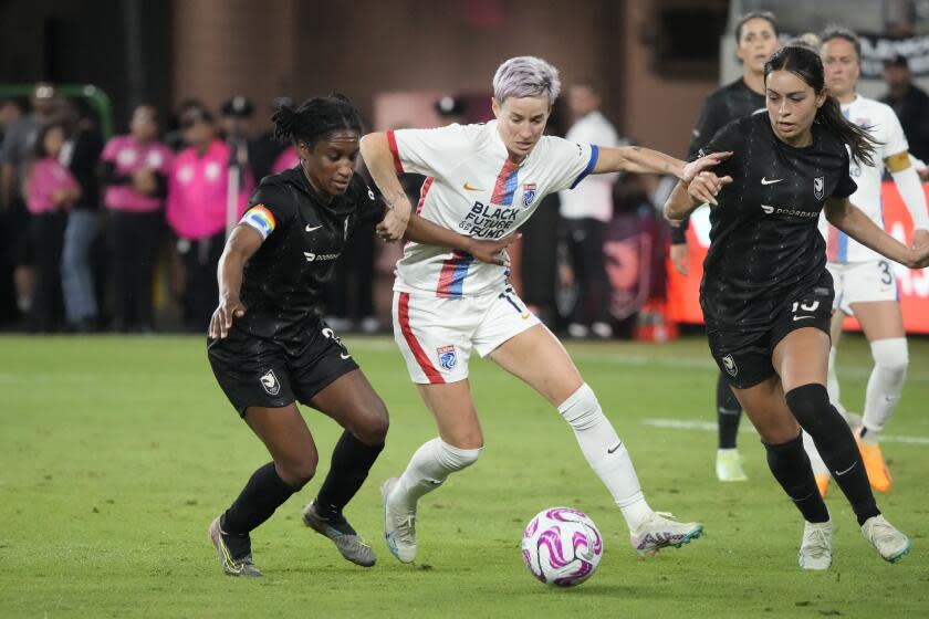 Angel City's Jasmyne Spencer, left, and Scarlett Camberos, right, defend against OL Reign's Megan Rapinoe during the second half of an NWSL soccer match Wednesday, April 19, 2023, in Los Angeles. (AP Photo/Marcio Jose Sanchez)