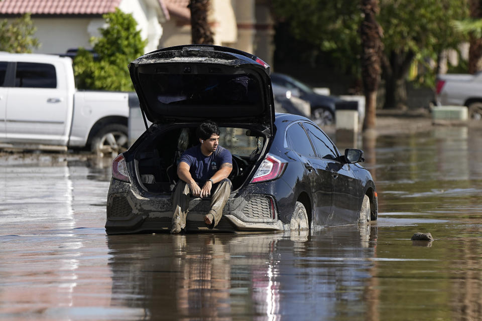 Dorian Padilla sits in his car as he waits for a tow after it got stuck in the mud on a street Monday, Aug. 21, 2023, in Cathedral City, Calif. Forecasters said Tropical Storm Hilary was the first tropical storm to hit Southern California in 84 years, bringing the potential for flash floods, mudslides, isolated tornadoes, high winds and power outages. (AP Photo/Mark J. Terrill)