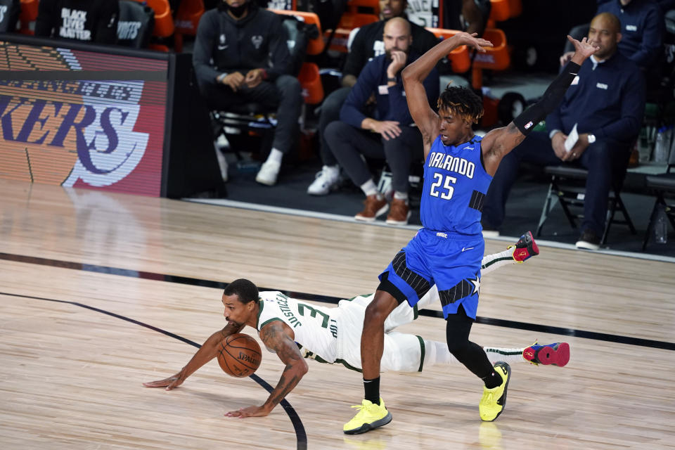 Milwaukee Bucks' George Hill (3) falls as Orlando Magic's Wes Iwundu (25) defends during the second half of an NBA basketball first round playoff game Saturday, Aug. 29, 2020, in Lake Buena Vista, Fla. (AP Photo/Ashley Landis)