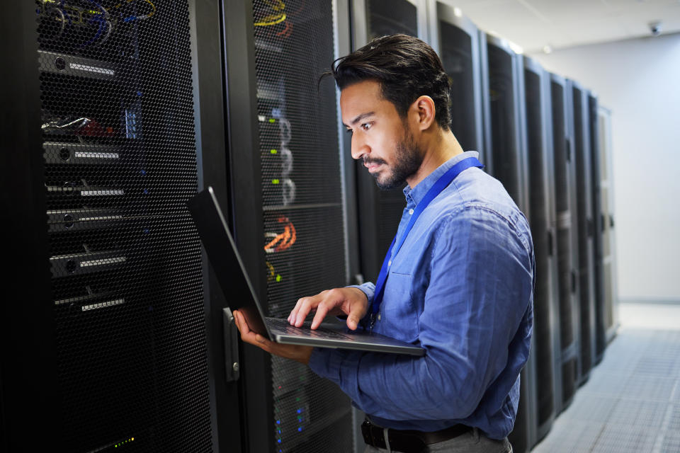 Programming, data center and a man with a laptop for maintenance, cyber security and internet check. Coding, email and an Asian programmer typing on a computer for network or server analytics