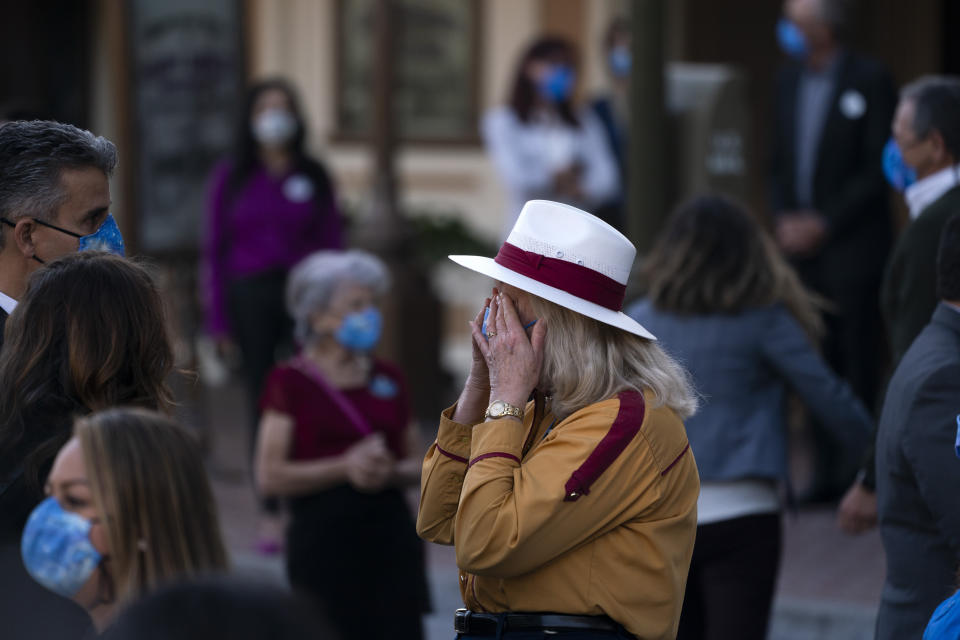 Employee Diane, who only gave her first name, wipes her tears after a flag raising ceremony at Disneyland in Anaheim, Calif., Friday, April 30, 2021. The iconic theme park in Southern California that was closed under the state's strict virus rules swung open its gates Friday and some visitors came in cheering and screaming with happiness. (AP Photo/Jae C. Hong)