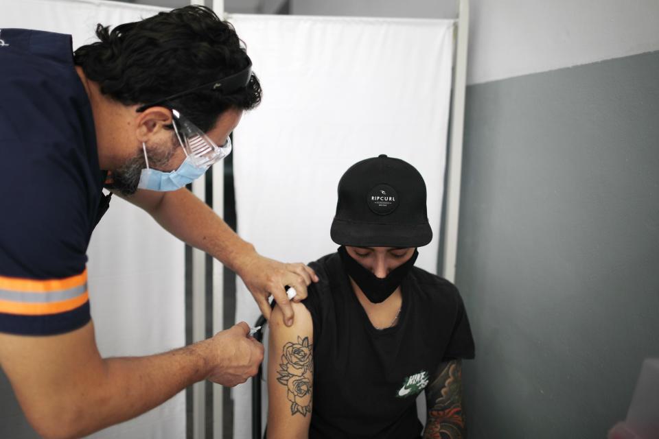 FILE - In this Feb. 18, 2021, file photo, health care worker Ezequiel Iglesias is injected with a dose of the Sputnik V COVID-19 vaccine at a Quilmes public school, on the outskirts of Buenos Aires, Argentina, as the country begins to vaccinate health care workers against the new coronavirus. Russia’s boast in August that it was the first country to authorize a coronavirus vaccine led to skepticism because of its insufficient testing on only a few dozen people. Now, with demand growing for the Sputnik V, experts are raising questions again, this time over whether Moscow can keep up with all the orders from countries that want it. (AP Photo/Natacha Pisarenko, File)