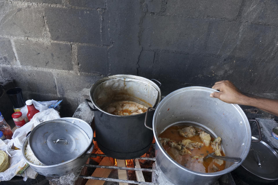 Migrants from Colombia cook a dish they call "American chicken" to sell to the other 3,000 migrants crammed in tents inside the Senda de Vida 2 shelter in Reynosa, Mexico, on Dec. 15, 2022. The shelter, the second founded by an evangelical pastor on this border city, houses migrants from Haiti, Central and South America in tents pitched on concrete or rough gravel, providing only the most essential care but security from the cartels that prey on migrants left outside. (AP Photo/Giovanna Dell'Orto)