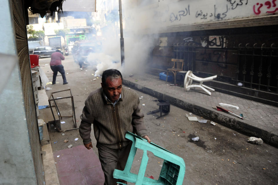 FILE - In this Saturday, Nov. 30, 2013 file photo, protesters and shopkeepers face teargas near a Cairo court where supporters of the April 6 youth group gathered to condemn the detention of 24 activists arrested Tuesday while taking part in a protest that was not authorized by authorities, in Cairo, Egypt. On Monday, April 7, 2014, an Egyptian appeals court has upheld convictions and three-year sentences for three prominent activists — Ahmed Maher, Mohammed Adel and Ahmed Douma. The three were accused of violating a controversial new law on holding protests. The ruling is part of a crackdown by Egypt's military-backed government against the leaders of the 2011 uprising that toppled the regime of autocrat Hosni Mubarak. (AP Photo/Ahmed Omar, File)