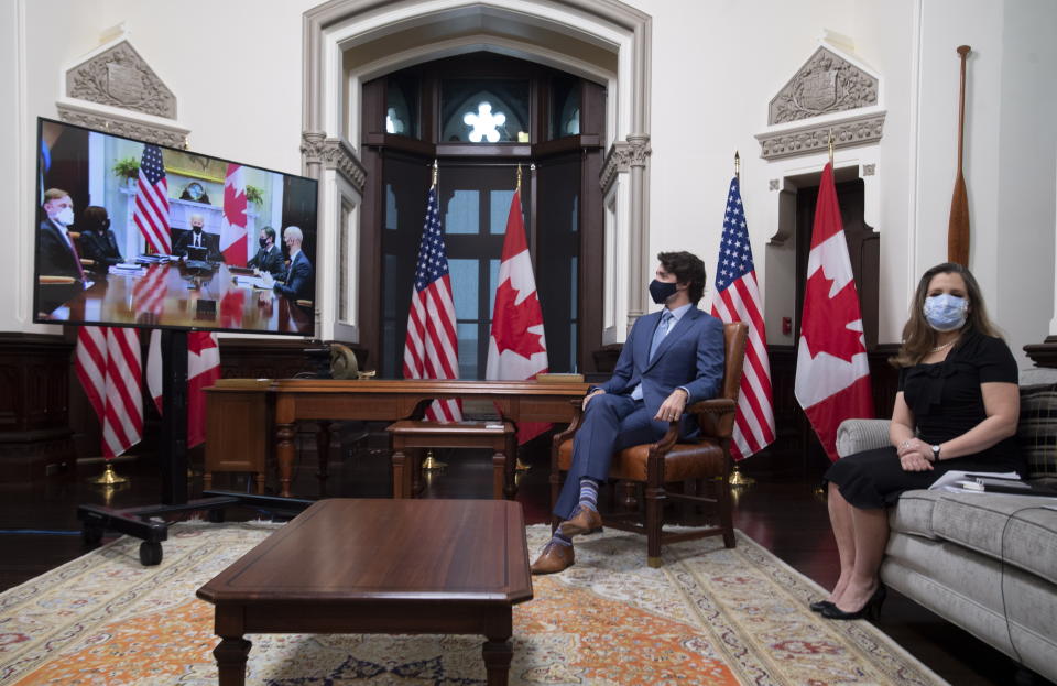 El primer ministro de Canadá, Justin Trudeau, y la viceprimera ministra y ministra de Finanzas, Chrystia Freeland, observan unas pantallas de televisión durante una reunión virtual con el presidente estadounidense Joe Biden, en su oficina en Ottawa, Canadá, el martes 23 de febrero de 2021. (Adrian Wyld/The Canadian Press vía AP)