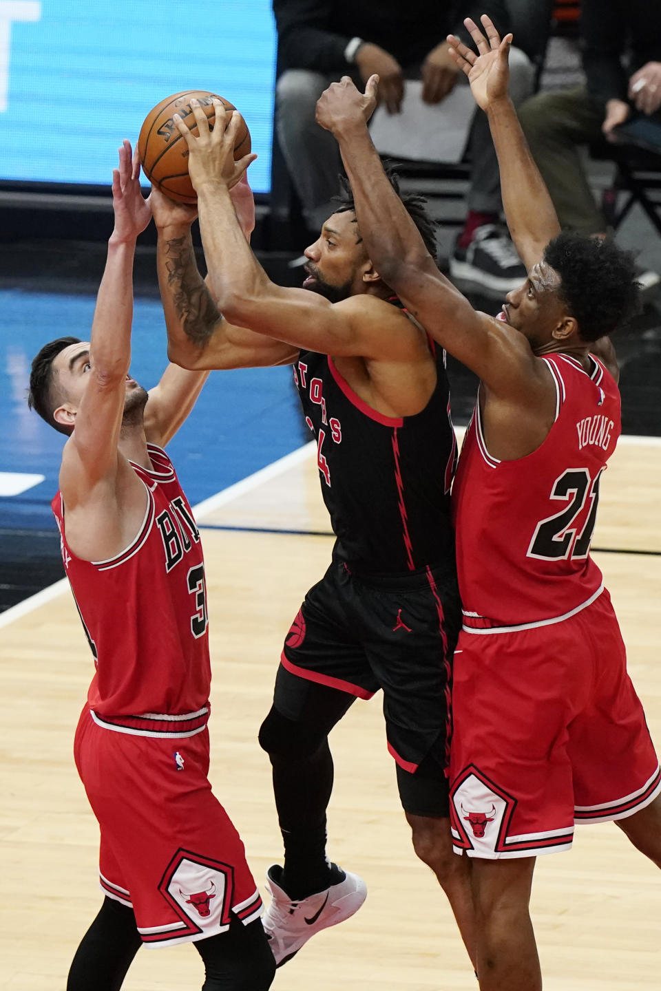 Toronto Raptors center Khem Birch, center, shoots from between Chicago Bulls guard Tomas Satoransky, left, and forward Thaddeus Young during the first half of an NBA basketball game in Chicago, Thursday, May 13, 2021. (AP Photo/Nam Y. Huh)