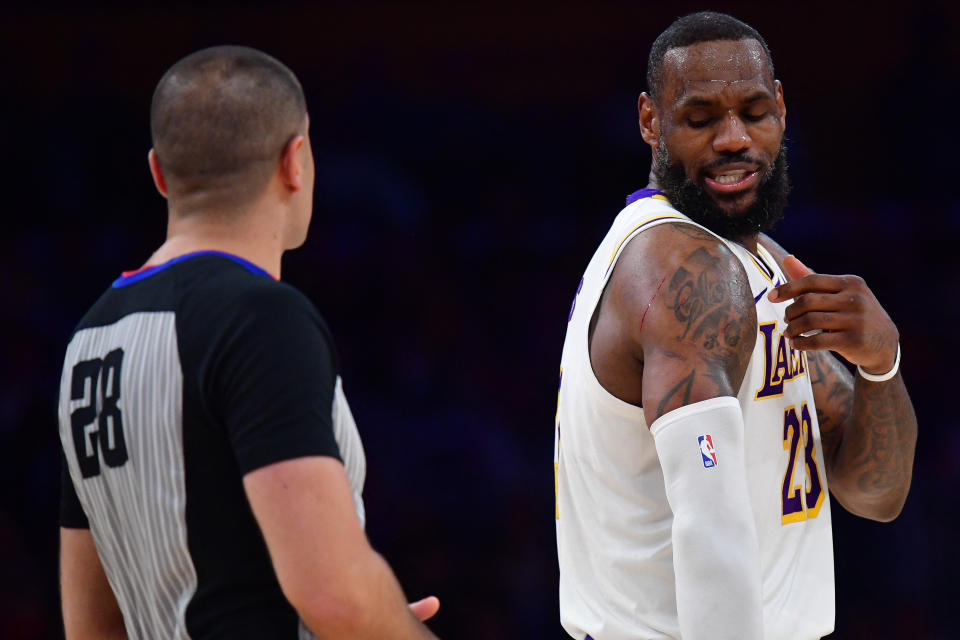 LeBron James shows referee Mousa Dagher his bloodied shoulder. (Gary A. Vasquez/Reuters)