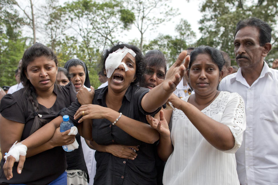 FILE- In this Wednesday, April 24, 2019 file photo, Anusha Kumari, center, weeps during a mass burial for her husband, two children and three siblings, all victims of Easter Sunday's bomb attacks, in Negombo, Sri Lanka. In an instant on Easter Sunday, Kumari, 43, was left childless and a widow when suicide bombers launched a coordinated attack on churches and luxury hotels in and just outside Sri Lanka's capital, Colombo. (AP Photo/Gemunu Amarasinghe, File)