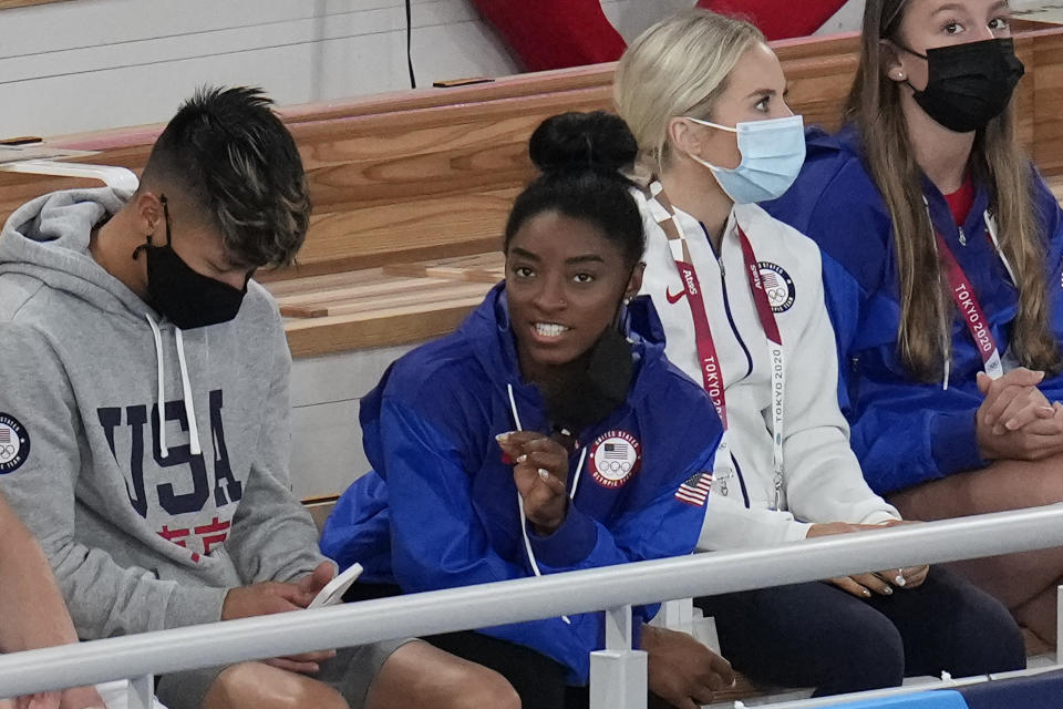 Simone Biles, of the United States, sits at the stands with teammates during the artistic gymnastics men's apparatus final at the 2020 Summer Olympics, Monday, Aug. 2, 2021, in Tokyo, Japan. (AP Photo/Gregory Bull)