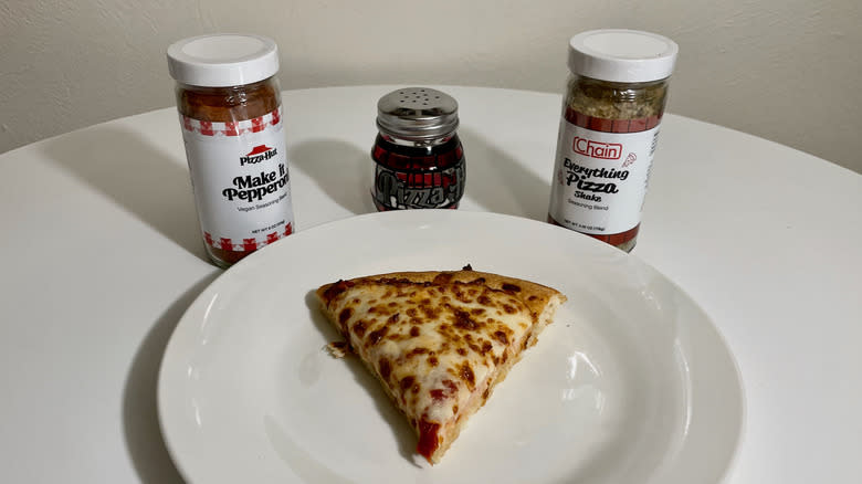 Seasonings, shaker, and pizza slice on plate