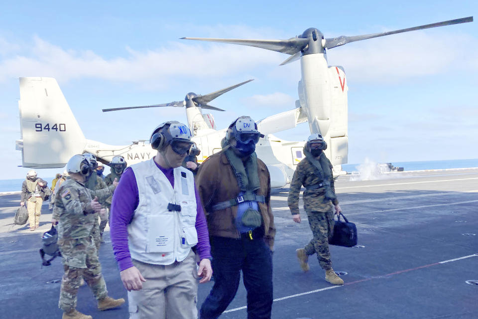 Defense Secretary Lloyd Austin, center, arrives on the aircraft carrier USS Nimitz, Thursday, Feb. 25, 2021, at sea. Austin told sailors on the USS Nimitz Thursday that he hopes to avoid long ship deployments like the more than 10 months they just spent at sea. But as he made his first aircraft carrier visit as Pentagon chief, he acknowledged the competing demands for American warships around the globe as he wrestles with security threats from China in the Pacific and Iran in the Middle East. The Nimitz, which left its homeport of Bremerton, Washington, last April, has been at sea for nearly 300 days, including several weeks of pre-deployment exercises. (AP Photo/Lolita Baldor)