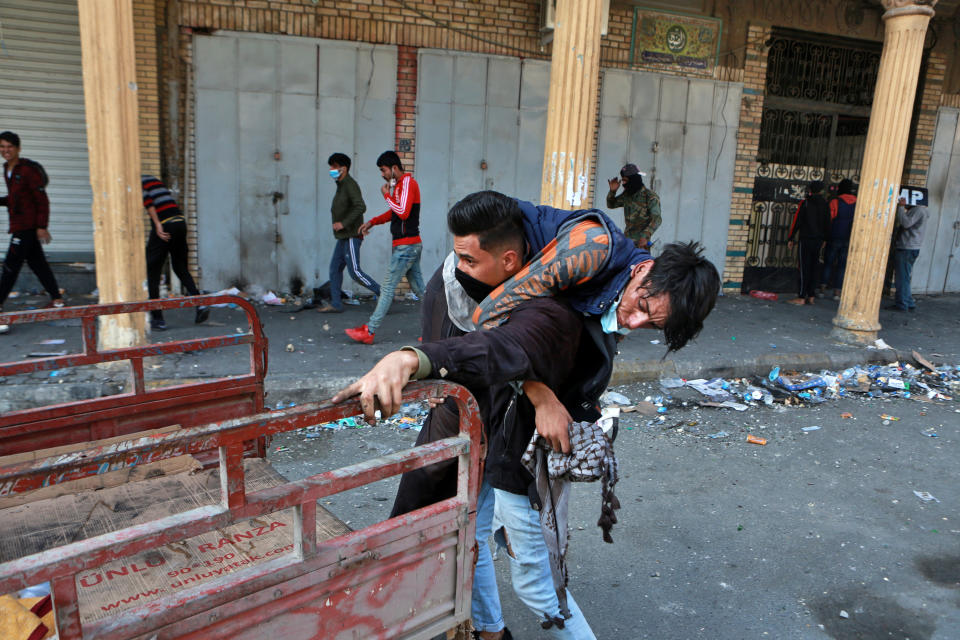 An injured protester is rushed to a hospital during clashes between security forces and anti-government protesters on Rasheed Street in Rasheed Street, Baghdad, Iraq, Tuesday, Nov. 26, 2019. (AP Photo/Khalid Mohammed)