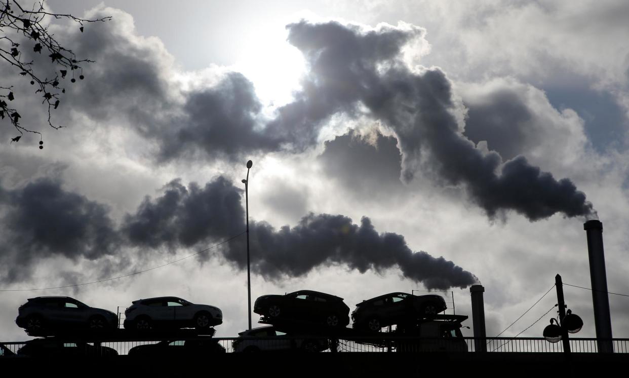 <span>Smoke rises from a factory as a lorry loaded with cars crosses a bridge in Paris.</span><span>Photograph: Michel Euler/AP</span>