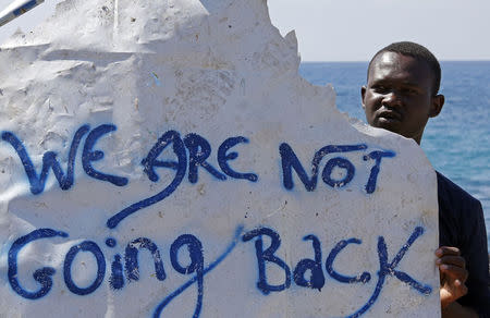 A migrant holds a banner at the Saint Ludovic border crossing on the Mediterranean Sea between Vintimille, Italy and Menton, France, June 15, 2015. REUTERS/Eric Gaillard