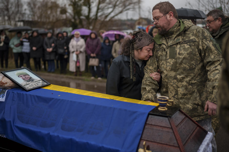 Relatives cry next to the coffin of Ukrainian Cpt. Serhii Vatsko in Boiarka, Ukraine, Friday, March 29, 2024. Vatsko, who was killed on the frontline of eastern Ukraine on March 24 joined the country's military in 2014. (AP Photo/Vadim Ghirda)