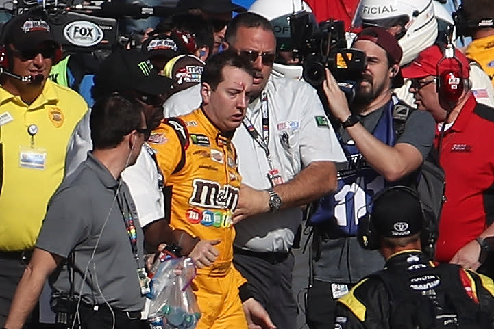 Kyle Busch is escorted away by a NASCAR official after an incident on pit road with Joey Logano. (Getty Images)