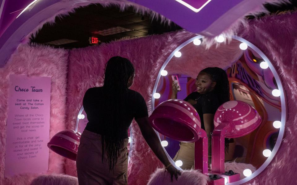 Nkemdilem Bernard, an influencer behind Detroit Finds 313, holds her phone as she stands on the Cotton Candy salon exhibit inside Choco Town Detroit at the Oakland Mall in Troy on Wednesday, March 15, 2023. 